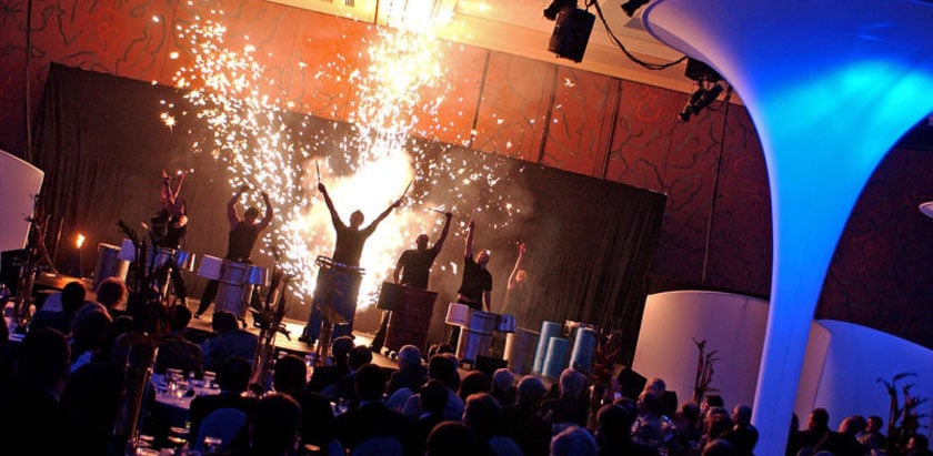 Tech conference audience facing a keynote stage with LED screens and modern lighting