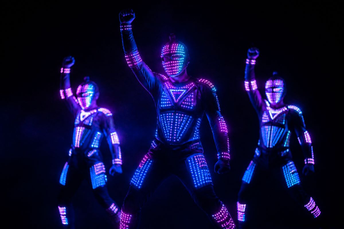 LED light suit dancers performing synchronized choreography in darkness
